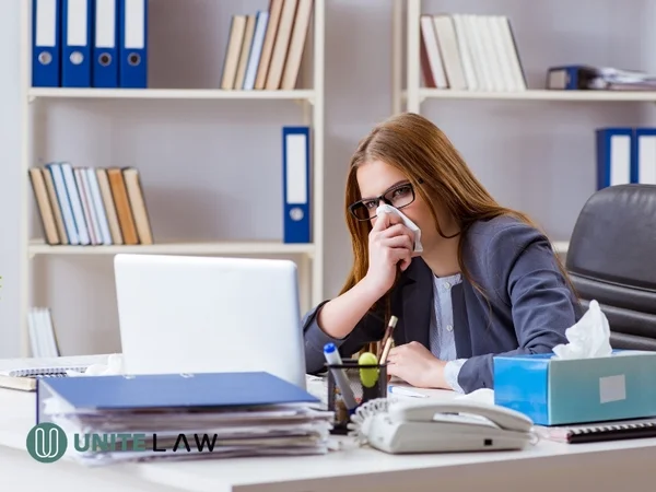 Employee working at an office desk while experiencing illness that may require family and medical leave.